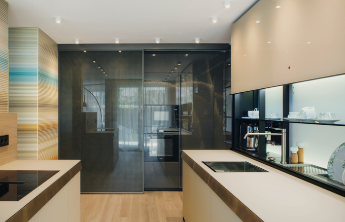 A fusion of function and design: kitchen design by Valcucine and sliding glass doors by Rimadesio; there is plenty of storage space behind them.
