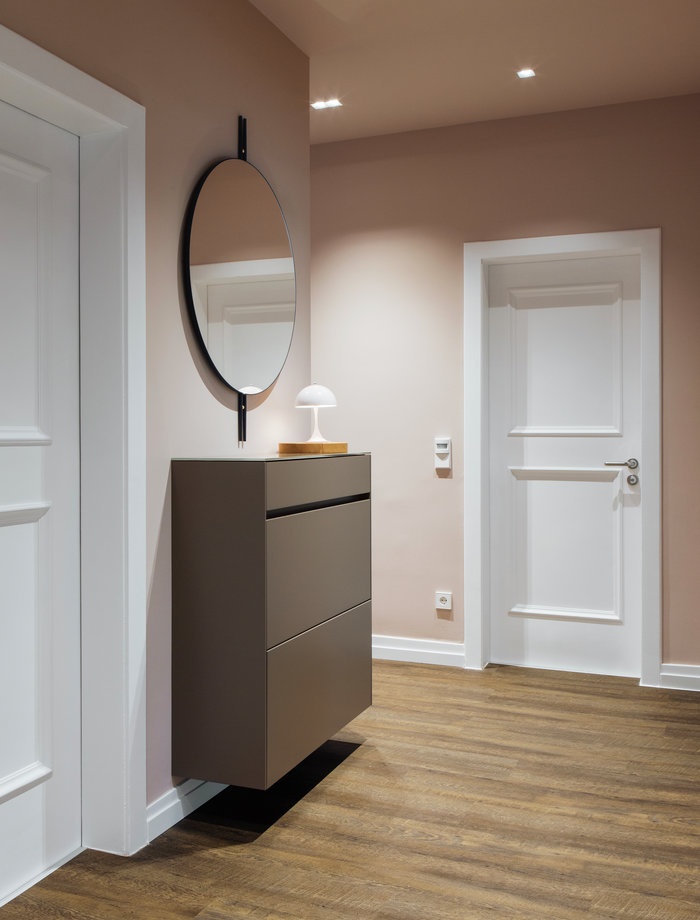 Welcoming atmosphere in pink: above the shoe cupboard by Schönbuch, a mirror by Gubi also visually extends the entrance area.